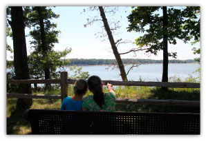 picture of kids watching a boat on a bench near the lake shoreline